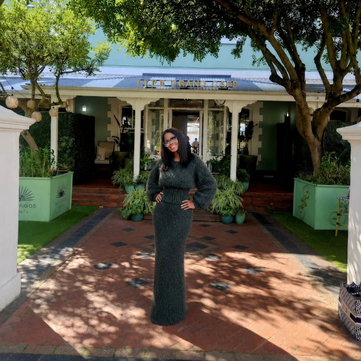 Woman in a green dress standing in front of a building with greenery